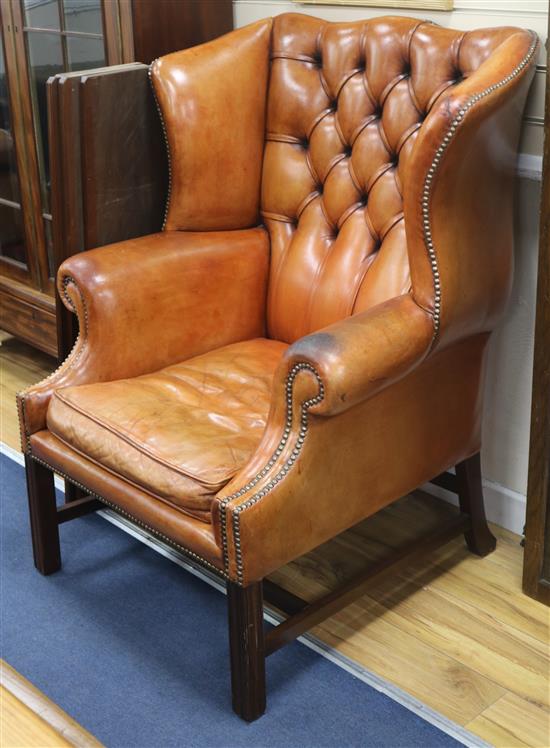 A pair of button back leather wing armchairs